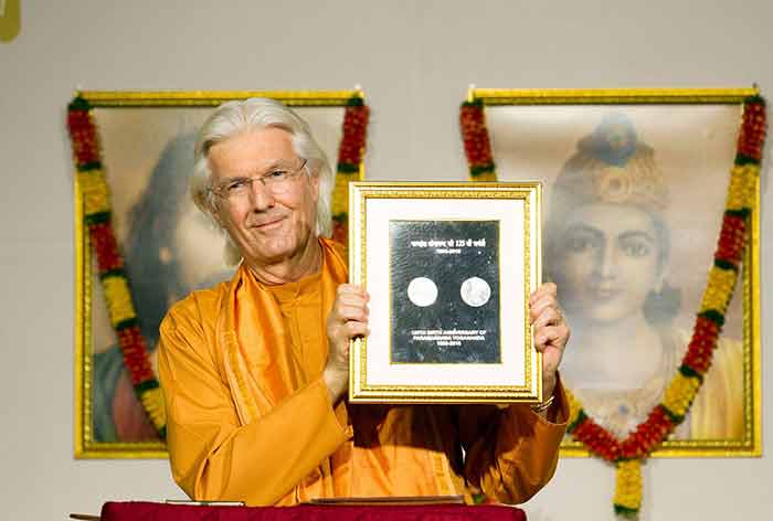 Swami Chidananda displaying the Commemorative Coin to the devotees.