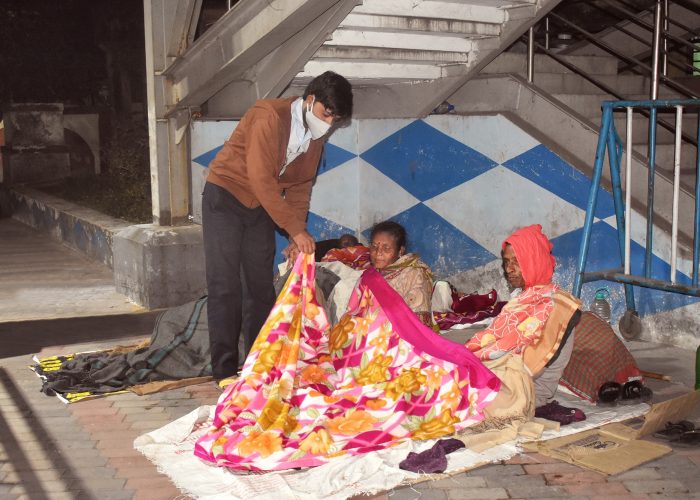 A volunteer distributes blankets at Dakshineswar station.